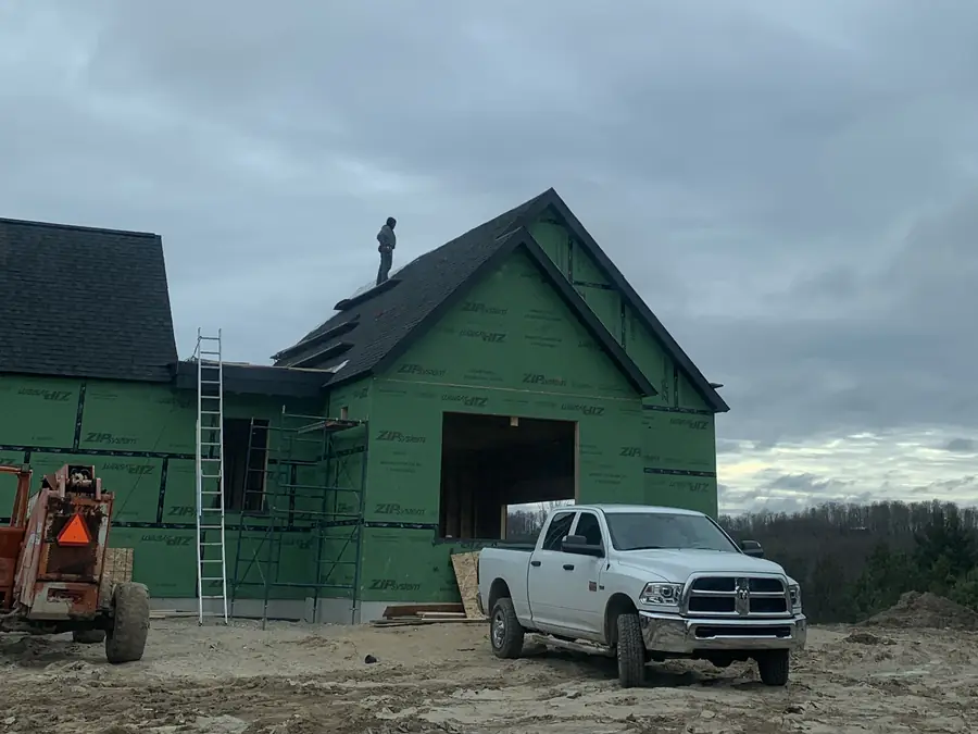 New construction home with sheathing and an AA Roofing roofer on the roof