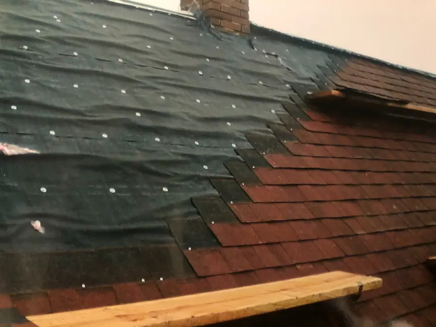 Re-roof in progress with new dark shingles replacing old red shingles
