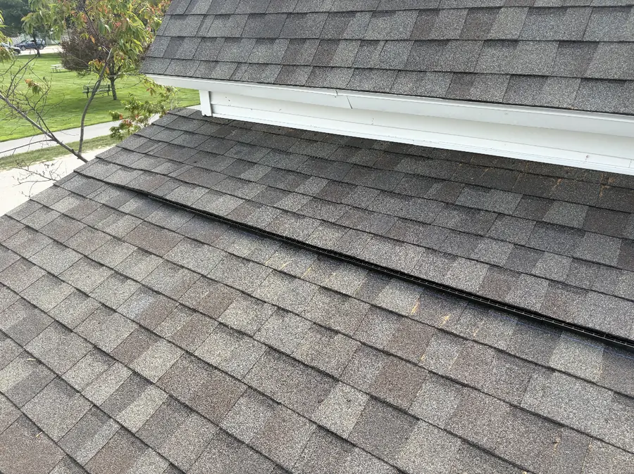 Finished roof with a new vent line shingled in along a dormer wall
